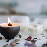 pexels-photo-7233912-7233912 Warm candle flame in ceramic holder with dried flowers on table.